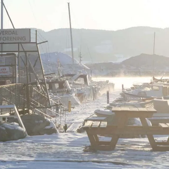 Verdal båteierforening med snø på bakken og båter i islagt havn.