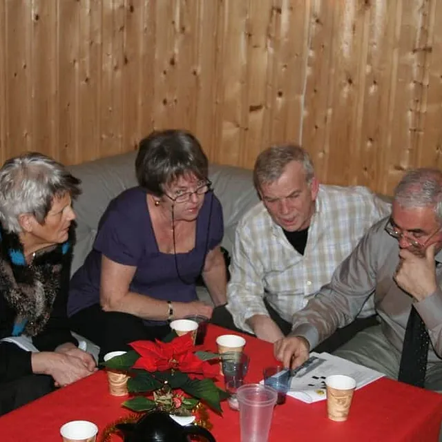 Fire personer sitter rundt bord innendørs og ser på dokumenter.